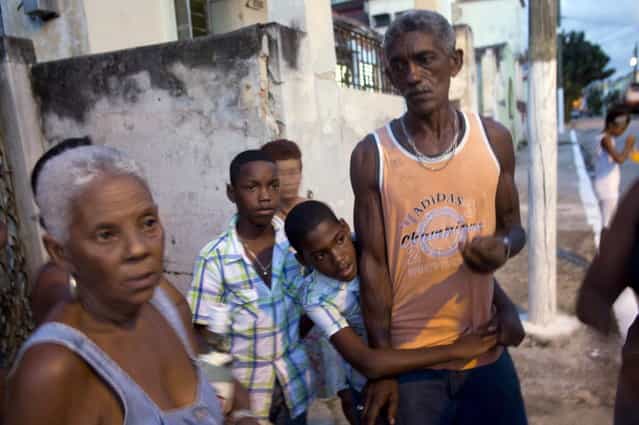 In this September 27, 2013 photo, Adrian Cueto, 11, center, embraces his father Ramon as his twin brother Arian looks on during interviews in Havana, Cuba. The Cueto brothers are just one set of twins out of 12 sets living along two consecutive blocks in western Havana. (Photo by Ramon Espinosa/AP Photo)