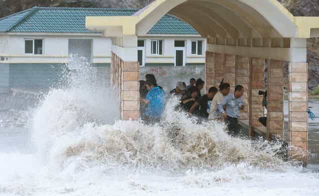People dodge as a storm surge hits the coastline under the influence of Typhoon Fitow in Wenling, Zhejiang province, October 6, 2013. China issued a red alert ahead of Typhoon Fitow, which landed at east of the country on early Monday, according to local media. (Photo by Reuters/China Daily)