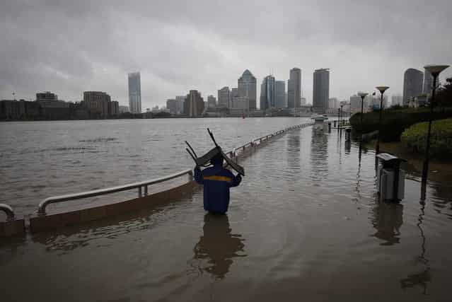 A person carries a chair through a flooded riverside park in Shanghai, China, Monday, October 7, 2013. A typhoon slammed into southeastern China on Monday with powerful winds and heavy rains that killed at least five people, cut power, canceled flights and suspended train services. (Photo by AP Photo)