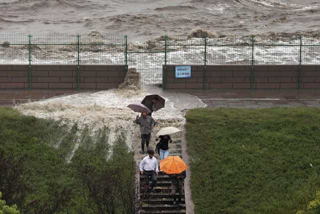 Visitors run down a stairway as tidal waves under the influence of Typhoon Fitow surge past a barrier in Haining, Zhejiang province October 7, 2013. Four people were killed and hundreds of thousands evacuated after Typhoon Fitow hit eastern China, destroying houses and farmlands and closing ports and airports. (Photo by Reuters/Stringer)