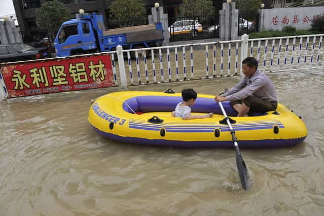 Residents make their way through a flooded street on an inflatable boat in disaster-hit Cangnan county of Wenzhou, east China's Zhejiang province, on October 7, 2013, where more than 1,200 homes collapsed and damages amounted to hundreds of millions of yuan. Typhoon Fitow barrelled into China's east coast, packing winds of more than 200 kilometres (125 miles) an hour, after hundreds of thousands of people were evacuated and bullet train services were suspended. At least three people were reported killed, all of them near the city of Wenzhou in Zhejiang province, the state broadcaster CCTV said. (Photo by AFP Photo)