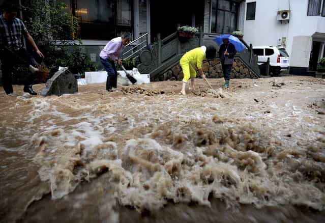 Residents dig a channel to prevent floodwater from reaching their homes in Hangzhou, in east China's Zhejiang province, Monday, October 7, 2013. A typhoon slammed into southeastern China on Monday with powerful winds and heavy rains that killed at least five people, cut power, canceled flights and suspended train services. (Photo by AP Photo)