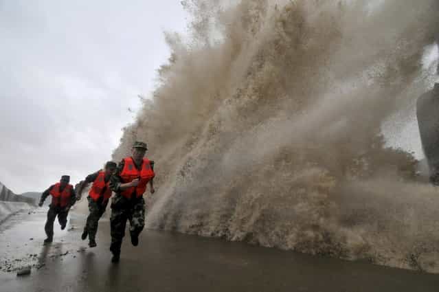 Frontier soldiers run as a storm surge hits the coastline under the influence of Typhoon Fitow in Wenling, Zhejiang province, October 6, 2013. China issued a red alert ahead of Typhoon Fitow, which is expected to lash east of the country on Sunday evening. (Photo by Reuters/China Daily)