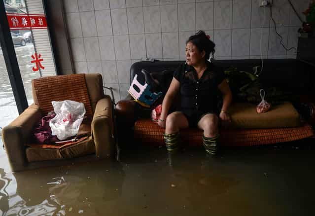In this photo provided by China's Xinhua News Agency, a woman rests as she sits in a flooded building in Cangnan County, east China's Zhejiang Province, Monday, October 7, 2013. Five people have been reported killed as a typhoon hit southeastern China on Monday with powerful winds and heavy rains causing widespread damage. (Photo by AP Photo/Xinhua News Agency)