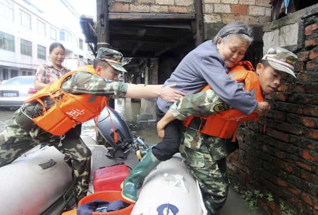 Paramilitary policemen carry an elderly woman off a raft as they rescue trapped residents after Typhoon Fitow hit Taizhou, Zhejiang province October 8, 2013. Four people were killed and hundreds of thousands evacuated after Typhoon Fitow hit eastern China, destroying houses and farmlands and closing ports and airports. (Photo by Reuters/China Daily)