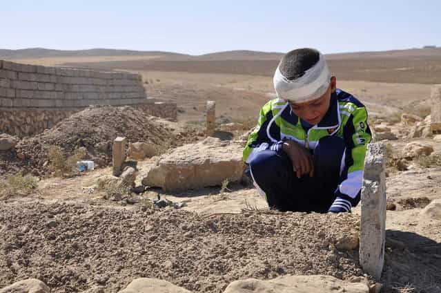 Mohammed Moses grieves by the grave of his father Oktober 7, 2013, who was killed Sunday by a suicide car bomb attack near the Qabak elementary school in the Shiite Turkomen village of Qabak, Iraq. (Photo by Asociated Press)