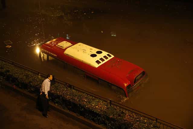 In this October 8, 2013. photo, a man looks at a passenger bus submerged in a flooded underpass in Songjiang district, Shanghai, China. Shanghai city officials closed more than 60 parks and the city zoo as residents waded through flood waters after heavy rains hit the financial hub in the aftermath of Typhoon Fitow. (Photo by AP Photo)