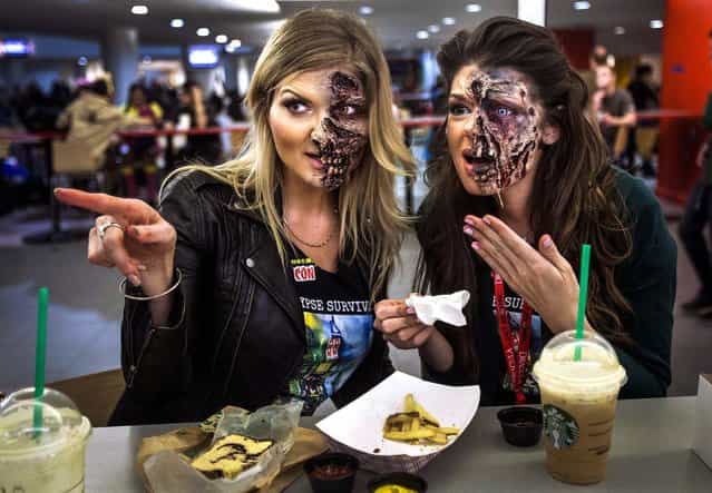 Makeup artists Kamila Wysocka and Alexis Jackson from Florida, point at another costumed person as they eat dinner in their zombie makeup at ComicCon in New York, on Oktober 10, 2013. (Photo by Carlo Allegri/Reuters)