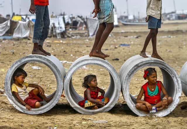 Children sitting inside cement water pipes play on the Marina beach in the southern Indian city of Chennai, on Oktober 10, 2013. (Photo by Reuters/Babu)