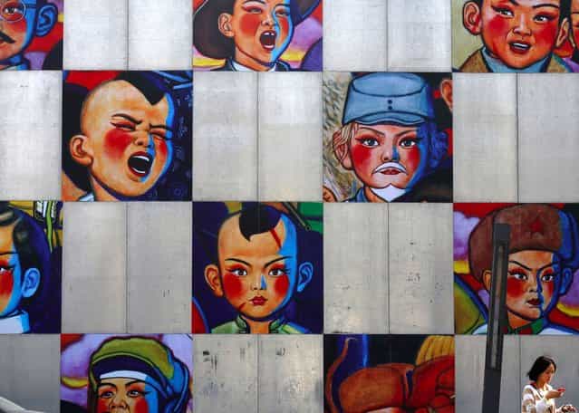 A woman walks past a gallery's wall bearing the paintings by Song Changqing during the 2013 Beijing 798 Art Festival at the 798 Art Zone in Beijing October 8, 2013. The art zone, originally an unused factory, was transformed into a landmark of contemporary art in Beijing in the 1990s. The annual art festival goes on till October 20. (Photo by Kim Kyung-Hoon/Reuters)