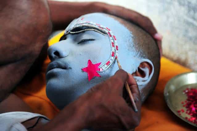 An Indian man applies make-up on a boy dressed as Hindu God Rama ahead of a religious procession during the Dussehra festival in Allahabad, on Oktober 10, 2013. (Photo by Sanjay Kanojia/AFP Photo)