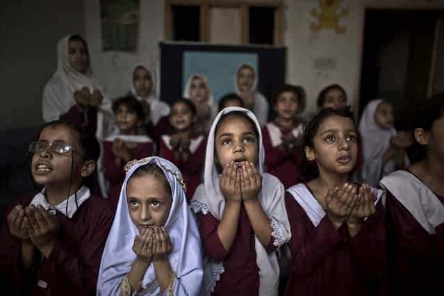 Schoolchildren chant prayers during a special class to recognize the anniversary of Malala Yousufzai's shooting by the Taliban, at a school in Rawalpindi, Pakistan, on Oktober 9, 2013. One year after a Taliban bullet tried to silence Malala's demand for education, she has published a book and is a contender for the Nobel Peace Prize. But the militants threaten to kill her should she dare return home from Britain to Pakistan, and the principal at her old school says that as Malala's fame has grown, so has fear in her classrooms. (Photo by Muhammed Muheisen/Associated Press)