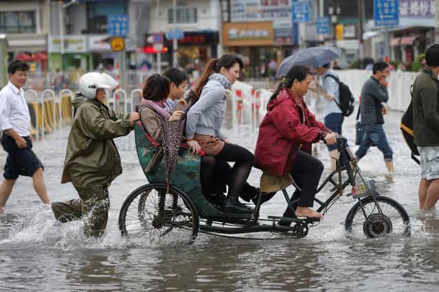Commuters ride on a tricycle cross a flooded road outside a subway station in Shanghai, China Tuesday, October 8, 2013. Typhoon Fitow slammed into southeastern China on Monday with powerful winds and heavy rains that killed at least five people, cut power, canceled flights and suspended train services. (Photo by AP Photo)