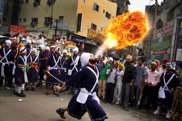 A Sikh youth performs an act of fire as he displays martial art skills during a religious procession on the eve of birth anniversary of Guru Ram Das in Amritsar, India, Tuesday, October 8, 2013. Ram Das was the fourth of the ten gurus of Sikhism. (Photo by Sanjeev Syal/AP Photo)
