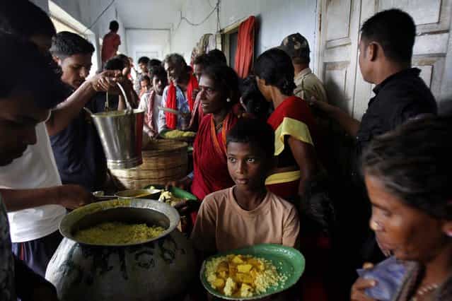 Evacuated Indian villagers eat food at a temporary cyclone shelter in Chatrapur in Ganjam district about 200 kilometers (125 miles) from the eastern Indian city Bhubaneswar, India, Saturday, October 12, 2013. Strong winds and heavy rains pounded India's eastern coastline Saturday, as hundreds of thousands of people took shelter from a massive, powerful Cyclone Phailin expected to reach land in a few hours. (Photo by Biswaranjan Rout/AP Photo)