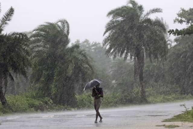 An Indian man holds an umbrella as he heads towards a cyclone shelter near Chatrapur in Ganjam district about 200 kilometers (125 miles) from the eastern Indian city Bhubaneswar, India, Saturday, October 12, 2013. Hundreds of thousands of people living along India's eastern coastline were taking shelter Saturday from a massive, powerful cyclone Phailin that was set to reach land packing destructive winds and heavy rains. (Photo by Biswaranjan Rout/AP Photo)