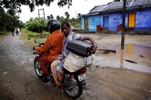An Indian couple drives towards a cyclone center, in village Podampeta, in Ganjam district about 200 kilometers (125 miles) from the eastern Indian city Bhubaneswar, India, Saturday, October 12, 2013. Strong winds and heavy rains pounded India's eastern coastline Saturday, as hundreds of thousands of people took shelter from a massive, powerful Cyclone Phailin expected to reach land in a few hours. (Photo by Biswaranjan Rout/AP Photo)