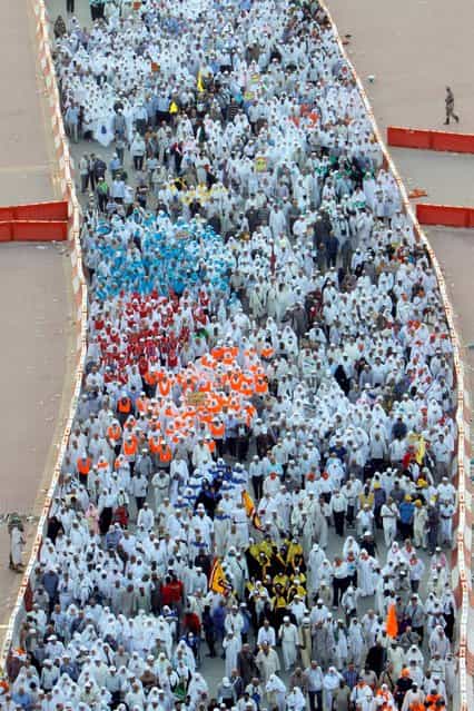 Muslim pilgrims walk to cast stones at pillars, symbolizing the stoning of Satan, in a ritual called [Jamarat], a rite of the annual hajj, in Mina near the holy city of Mecca, Saudi Arabia, Wednesday, October 16, 2013. More than 2 million pilgrims – about 1 million fewer than last year – are performing the hajj, a central pillar of Islam and one that able-bodied Muslims must make once in their lives as a four-day spiritual cleansing based on centuries of interpretation of the traditions of Prophet Muhammad. (Photo by Amr Nabil/AP Photo)
