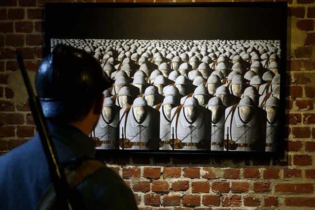A historical reenactor wearing a Poliu (French soldier in World War I) uniform looks at a contemporary painting by Sebastien Roche titled [Les Sans-Visages] (Without Faces) during an exhibition about World War I at the fort of Seclin near Lille, France, on Oktober 13, 2013. (Photo by Pascal Rossignol/Reuters)