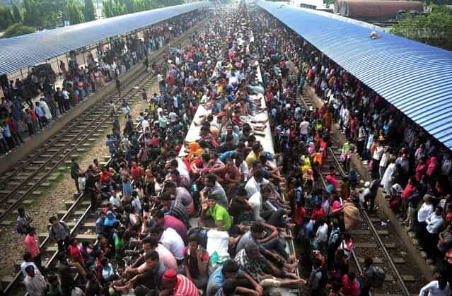 Bangladeshi Muslims travel on the roof of a train as they head to their homes ahead of Eid al-Adha as others wait at a railway station in Dhaka, Bangladesh, Tuesday, October 15, 2013. Hundreds of thousands of people working in Dhaka return home to spend time with their family during the Eid al-Adha celebrations. (Photo by AP Photo)