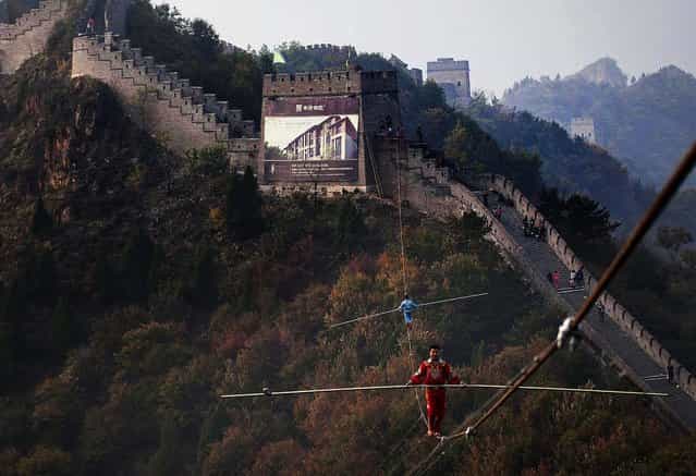 Adili Wuxor (front), who is known as [Prince of the Tightrope], and his apprentice walk on a tightrope above the Great Wall in Tianjin, on Oktober 18, 2013. (Photo by China Daily)