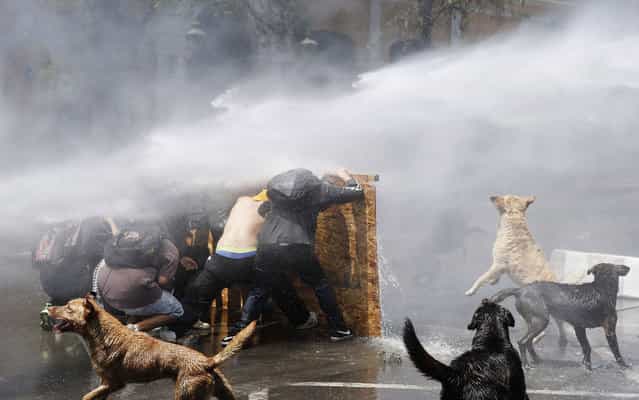 Demonstrators are hit by a jet of water as they clash with riot police during a protest to demand changes to the public education system in Santiago, Chile, on Oktober 17, 2013. (Photo by Ivan Alvarado/Reuters)