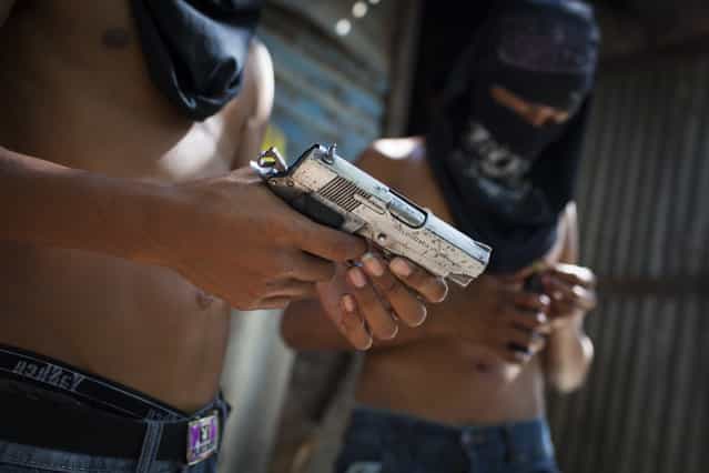 Mara Salvatrucha (MS) gang members with their weapons in Las Victorias district of San Salvador. In March 2012, the two largest gangs in El Salvador – the Mara Salvatrucha (MS) and the Barrio 18 (M18) – agreed on a truce following secret negotiations between gang leaders in prison which were mediated by a bishop and a former rebel leader. It is unclear whether the decision was the idea of the gangs themselves or whether they were encouraged by the government. The murder and kidnapping rate has fallen significantly since the beginning of the truce but it remains unclear how long the truce will hold. (Photo by Adam Hinton)