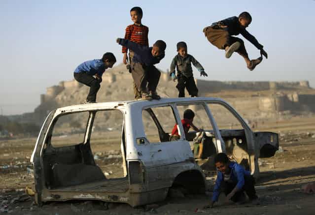 Afghan boys play on a destroyed car in Kabul October 22, 2013. (PhotobyMohammad Ismail/Reuters)