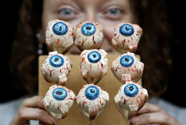 Cake Artist Sarah King displays her eyeball cakes at the [Feed the Beast extreme cake shop] in London, Thursday, October 24, 2013. The Halloween themed cake shop will have a 6ft long devil horse cake dripping blood, and the giant rotting maggot riddled section of a Kraken eye. Smaller items include rotting chocolate hands and feet, wound cupcakes and maggot topped gluten free cupcakes, it is open at The Rag Factory near Brick Lane in London on October 26 and 27. (Photo by Kirsty Wigglesworth/AP Photo)