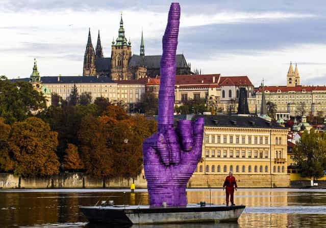 A worker looks up at an installation by Czech l artist David Cerny on a floating platform in front of the Prague Castle, on Oktober 21, 2013. Cerny said the piece was a reaction to the current political situation in the country and upcoming early elections, as well as its location, pointing towards the presidential residence at Prague Castle. (Photo by David W. Cerny)