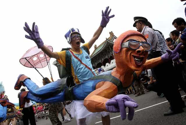 A man wearing a papier-mache figure shows his spirit as he marches during the [Dream Parade] in Taipei, Taiwan, on Oktober 19, 2013. (Photo by Chiang Ying-ying/Associated Press)