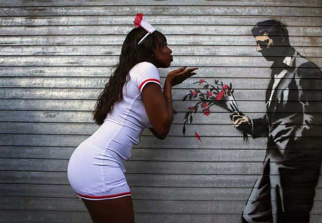A dancer poses with a new installation of art by British graffiti artist Banksy painted on the front door of the Hustler Club in New York, October 24, 2013. Known for his anti-authoritarian black-and-white stenciled images, which have sold at auction for upwards of $2 million, the British street artist is treating New Yorkers to a daily dose of spray-painted art – while eluding the police and incurring the wrath of New York Mayor Michael Bloomberg. (Photo by Eric Thayer/Reuters)
