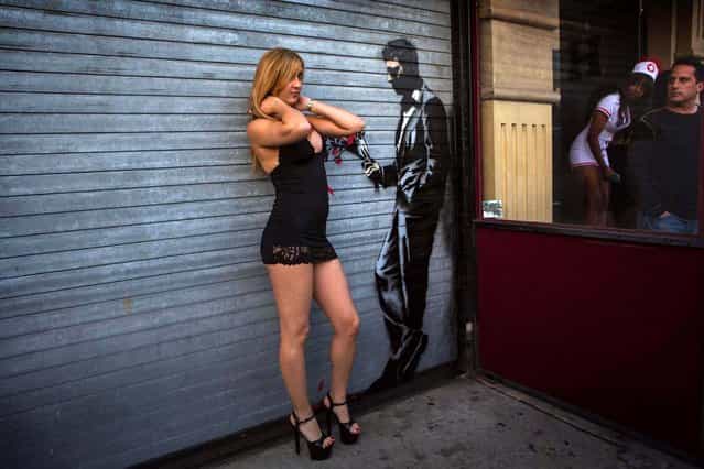 A dancer poses with the Banksy painting. (Photo by Eric Thayer/Reuters)