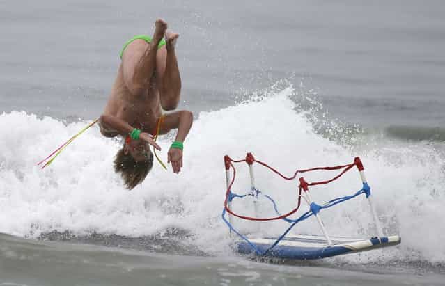 A man dressed as a wrestler in a ring, does a back flip off his surfboard, as he competes in the ZJ Boarding House Halloween Surf Contest in Santa Monica, California October 26, 2013. (Photo by Lucy Nicholson/Reuters)