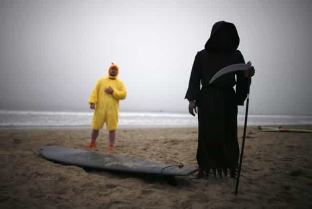 Sean Owolo, 40, (R) dressed as the Grim Reaper, and Marius Petrulis, 36, dressed as a chicken, prepare to compete in the ZJ Boarding House Halloween Surf Contest in Santa Monica, California October 26, 2013. (Photo by Lucy Nicholson/Reuters)