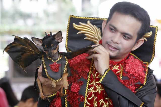 A pet owner holds up his dog which is dressed in a Dracula costume during the Scaredy Cats and Dogs Halloween costume competition in Manila. (Photo by Romeo Ranoco/Reuters)
