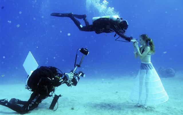 A model opens her mouth to breathe from a scuba tank as Israeli photographer Johannes Felten (L) takes pictures during an underwater photo shoot in the Red Sea in the resort city of Eilat October 22, 2013. A shipwreck was a popular location at this year's Eilat Red Sea shootout, where underwater photographers from around the world hussled for three days to capture the best images. (Photo by Gabriel Rif/Reuters)