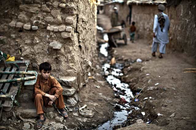 An Afghan refugee youth, sits on the side of the alley of a poor neighborhood, on the outskirts of Islamabad, Pakistan, Tuesday, October 29, 2013. Pakistan hosts over 1.6 million registered Afghans, the largest and most protracted refugee population in the world, according to the U.N. refugee agency, thousands of them still live without electricity, running water and other basic services. (Photo by Muhammed Muheisen/AP Photo)