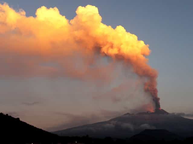 Smoke billows during an eruption of Mount Etna volcano as seen from the village of Viagrande, near the Sicilian town of Catania, Italy, Saturday, October 26, 2013. Mount Etna, Europe's most active volcano, has erupted, sending up a towering plume of ash visible in much of eastern Sicily. Etna's eruptions are not infrequent, although the last major one occurred in 1992. Catania airport said the eruption Saturday forced closure of nearby air space before dawn, but authorities lifted the closure in early morning. Several inhabited villages dot the mountain's slopes, but evacuations weren't necessary despite the lava flow. (Photo by Carmelo Imbesi/AP Photo)