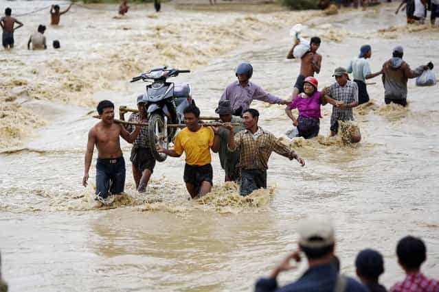 People wade through water as they cross a road that has been cut off from traffic by flash floods following heavy rain in Minhla township, Magwe district October 28, 2013. (Photo by Damir Sagolj/Reuters)