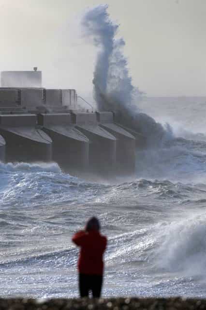 People watch the waves batter into the sea wall of a marina in Brighton, south England, Monday, October 28, 2013. A major storm with hurricane force winds is lashing much of Britain, causing flooding and travel delays including the cancellation of roughly 130 flights at London's Heathrow Airport. Weather forecasters say it is one of the worst storms to hit Britain in years. (Photo by Sang Tan/AP Photo)