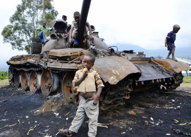 Children play on a burned tank which formerly belonged to M23 rebel soldiers, in Kimbumba, on October 31, 2013. The day before, DR Congo troops captured the last stronghold of M23 rebels in the troubled east of the country, raising hopes of a return to the negotiating table. (Photo by Junior D. Kannah/AFP Photo)