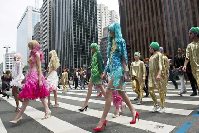 Models wear creations by FH for Fause Haten along Paulista Avenue during the presentation of the 2014 Winter collections of the Sao Paulo Fashion Week in Sao Paulo, Brazil, on Oktober 30, 2013. (Photo by Nelson Almeida/AFP Photo)