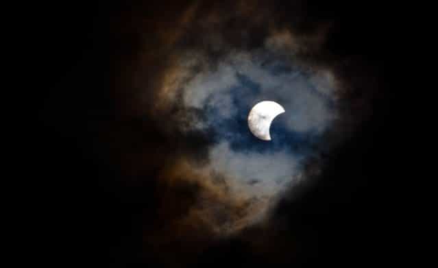 This picture taken on November 3, 2013 shows a rare hybrid solar eclipse through clouds from the Canary Island of Tenerife. A rare solar eclipse swept across parts of Africa, Europe and the United States today as the moon blocks the sun either fully or partially, depending on the location. The width of the shadow of the eclipse was 58 km and the maximum duration of totality, the maximum time that the moon covered the sun completely, was 1m 40s, on the Spanish Canary island of Tenerife. (Photo by Desiree Martin/AFP Photo)