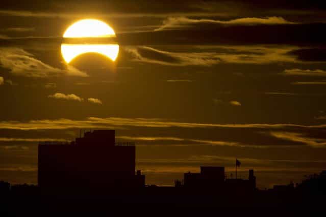 A partial Solar eclipse is seen just after sunrise over the Queens borough of New York across the East River on November 3, 2013 in New York. (Photo by Stan Honda/AFP Photo)