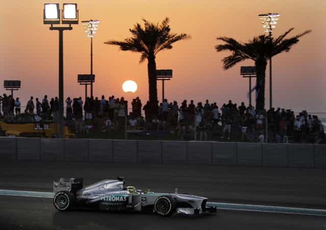 As the moon crosses in front of the sun during the partial solar eclipse, Mercedes driver Nico Rosberg of Germany steers his car during the Abu Dhabi Formula One Grand Prix at the Yas Marina racetrack in Abu Dhabi, United Arab Emirates. (Photo by Kamran Jebreili/Associated Press)