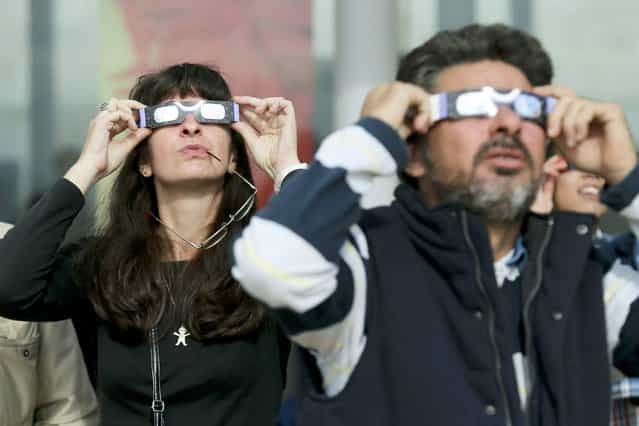 People use special spectacles allowing them to watch a rare solar eclipse showing the Sun partially blocked by the Moon passing in front, as seen in Estoril near Lisbon, Portugal, 03 November 2013. (Photo by Miguel A. Lopes/EPA/EFE)