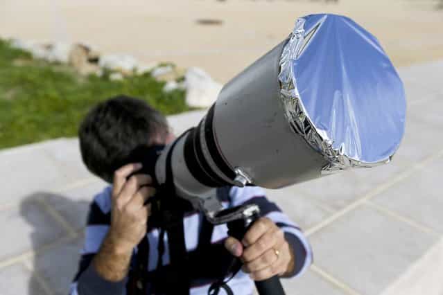 A man has aluminium foil stretched over the lens of his camera as he tries to take images of a rare solar eclipse showing the Sun partially blocked by the Moon passing in front, in Estoril near Lisbon, Portugal, 03 November 2013. (Photo by Miguel A. Lopes/EPA/EFE)