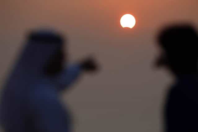 Kuwaiti men watch a partially solar eclipse at Souq Sharq Marina in Kuwait City on November 3, 2013. A rare solar eclipse will sweep across parts of Africa, Europe and the United States as the moon blocks the sun either fully or partially, depending on the location. (Photo by Yasser Al-Zayyat/AFP Photo)