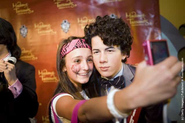 Maddy Pomilla, 14, from Huntingtown, MD, takes a picture of herself with a wax figure of Nick Jonas of the Jonas Brothers at Madame Tussauds